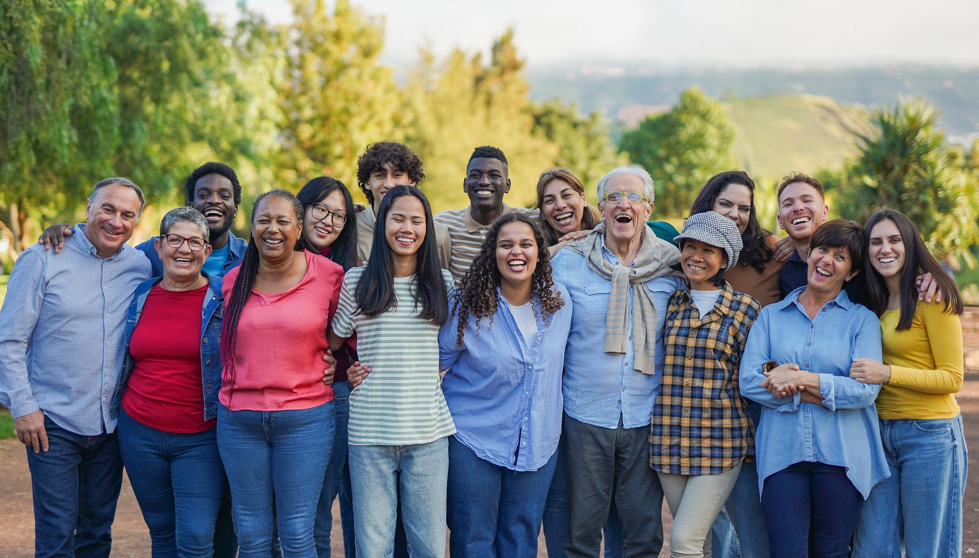 Crowd of multiracial people hugging each other and smiling in front of camera - Community and humaity concept