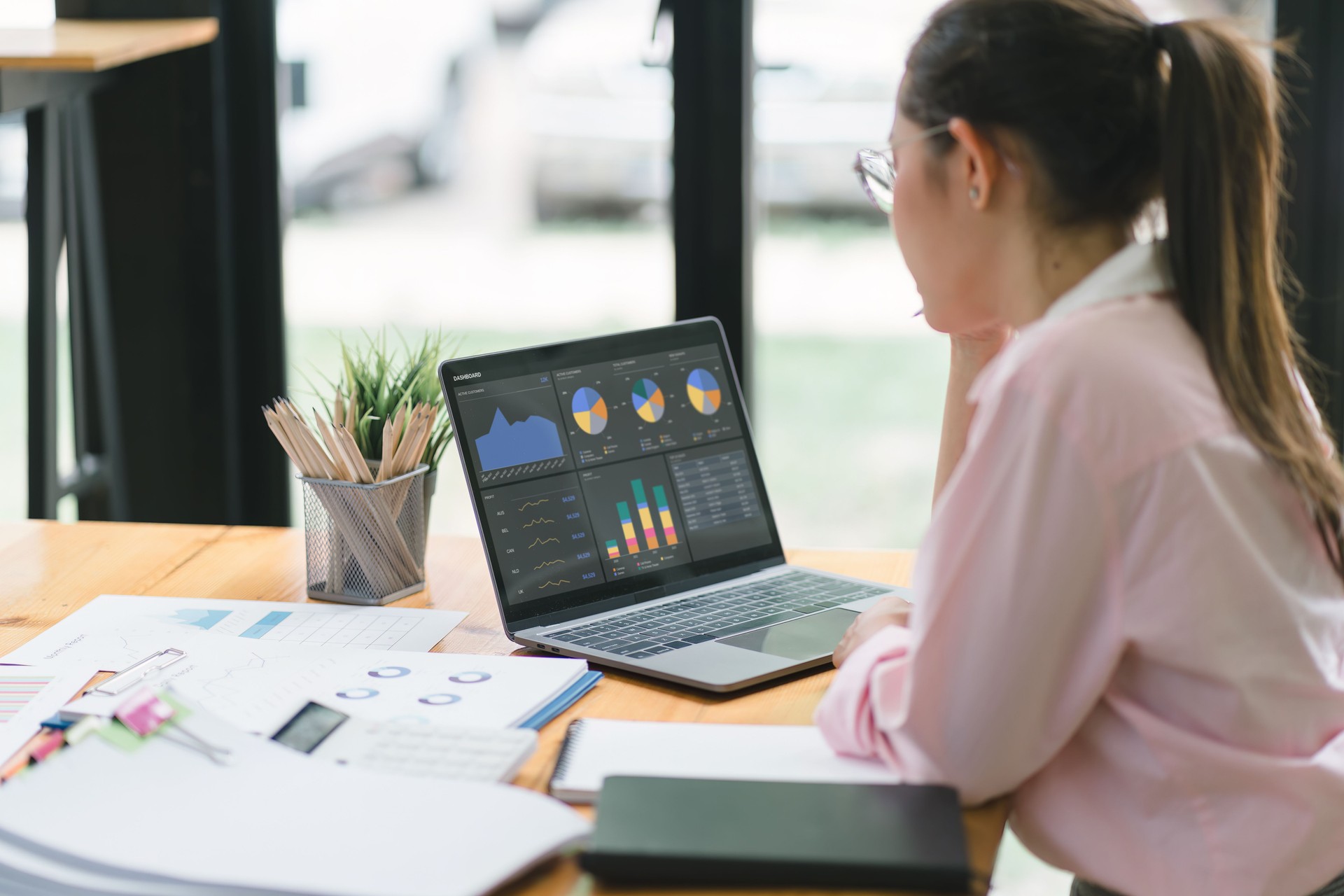 The data analyst woman working on a business analytics dashboard, utilizing charts and metrics to analyze performance and generate insightful reports for operations management.